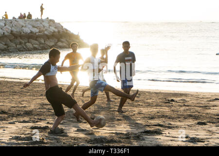 BADUNG,BALI/INDONESIA-aprile 02 2019: Asian adolescente di giocare a calcio o di calcio in spiaggia con il tramonto o golden ore sfondo Foto Stock