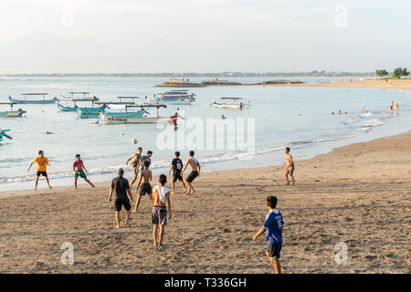 BADUNG,BALI/INDONESIA-aprile 02 2019: Asian adolescente di giocare a calcio o di calcio a Kuta beach con il tramonto o golden ore sfondo. Alcune tradizionali boa Foto Stock