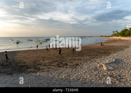 BADUNG,BALI/INDONESIA-aprile 02 2019: Asian adolescente di giocare a calcio o di calcio a Kuta beach con il tramonto o golden ore sfondo.Il cielo è nuvoloso e Foto Stock