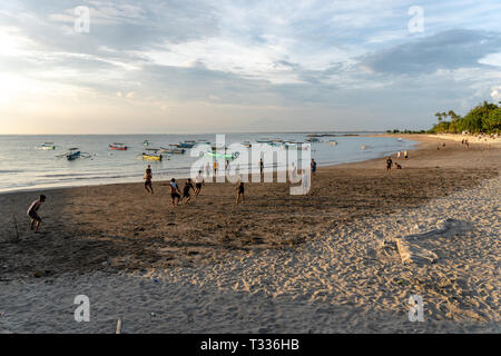 BADUNG,BALI/INDONESIA-aprile 02 2019: Asian adolescente di giocare a calcio o di calcio a Kuta beach con il tramonto o golden ore sfondo.Il cielo è nuvoloso e Foto Stock