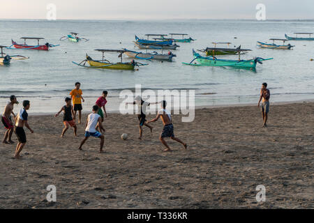 BADUNG,BALI/INDONESIA-aprile 02 2019: Asian adolescente di giocare a calcio o di calcio a Kuta beach con il tramonto o golden ore sfondo.Il cielo è nuvoloso e Foto Stock