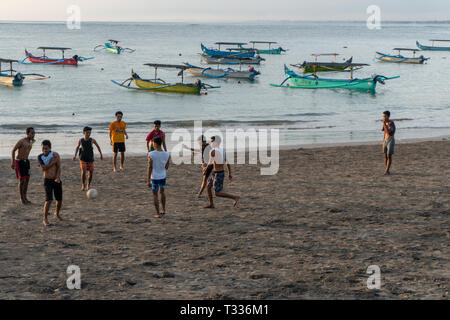 BADUNG,BALI/INDONESIA-aprile 02 2019: Asian adolescente di giocare a calcio o di calcio a Kuta beach con il tramonto o golden ore sfondo.Il cielo è nuvoloso e Foto Stock