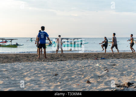 BADUNG,BALI/INDONESIA-aprile 02 2019: Asian adolescente di giocare a calcio o di calcio a Kuta beach con il tramonto o golden ore sfondo.Il cielo è nuvoloso e Foto Stock