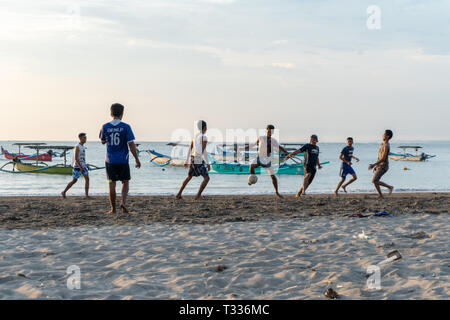 BADUNG,BALI/INDONESIA-aprile 02 2019: Asian adolescente di giocare a calcio o di calcio a Kuta beach con il tramonto o golden ore sfondo.Il cielo è nuvoloso e Foto Stock