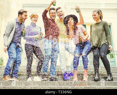 Gruppo di amici felice avente una parte di strada bere birre mentre i confetti sono rientranti verso il basso - esilarante giovani per festeggiare un compleanno per esterno Foto Stock