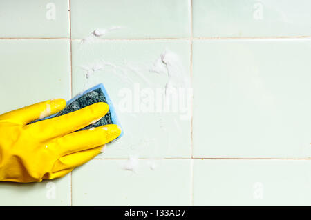 Una mano umana di lavaggio per la pulizia della superficie piastrellata in bagno o in cucina Foto Stock