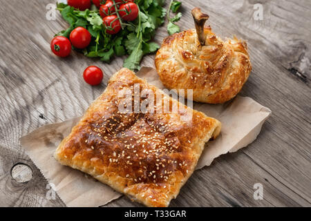 Fast food nazioni dell Est. Samsa e gamba di pollo su un piatto di portata con il coriandolo e verdure. In casa la cottura. Foto Stock