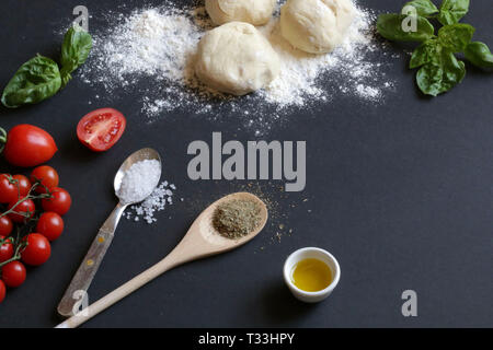 La pizza fatta in casa. Ingredienti per fare la pizza italiana su sfondo scuro. Foto Stock