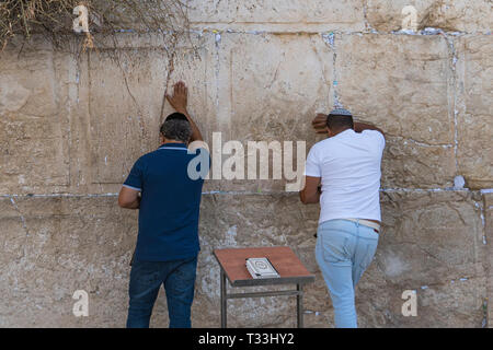 Gli uomini ebrei in preghiera al Muro Occidentale, importante religiosa ebraica sito nella città vecchia di Gerusalemme, Israele. Due uomini in abiti casual e kippa sul Foto Stock