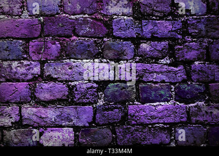Close-up di un muro di mattoni di porpora, di colore rosa e nero mattone. Muro di mattoni dipinto in colori luminosi. violaceo mattoni nel muro. Foto Stock