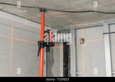 Misurazione laser durante i lavori di ristrutturazione. Costruzione di strumenti e apparecchiature. Luce laser rossa linee per misura di livello a. Foto Stock