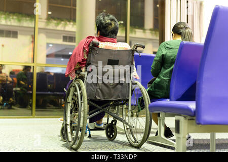 Senior donna in carrozzella con figlia al gate di partenza. Foto Stock