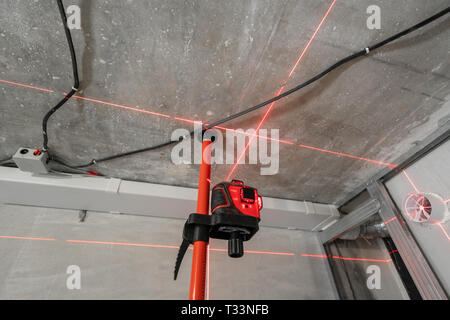 Misurazione laser durante i lavori di ristrutturazione. Costruzione di strumenti e apparecchiature. Luce laser rossa linee per misura di livello a. Foto Stock