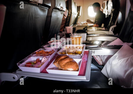 Pranzo in aereo. Di bordo per la classe economy pasto sul vassoio: burro, pane, insalata di pollo. Frutti: cocomero, ananas e kiwi gold. Piatto caldo: riso con Foto Stock