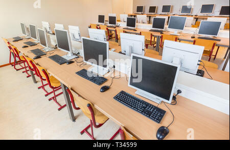 Classe Computer con file di computer desktop i tavoli e le sedie in alta scuola Foto Stock