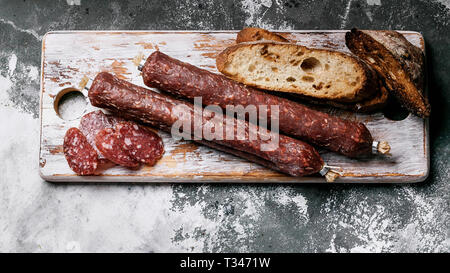 Banner di cibo. Salsiccia affumicata e ciabatta su un tagliere. Azienda prodotto naturale. Close-up Foto Stock