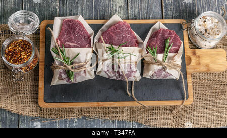 Raw bistecche di carne e verdure. Carni fresche su un tagliere. Vista superiore Foto Stock