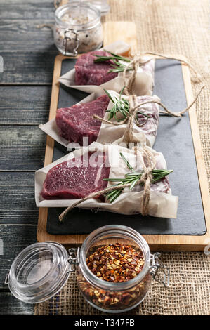 Raw bistecche di carne e verdure. Carni fresche su un tagliere Foto Stock