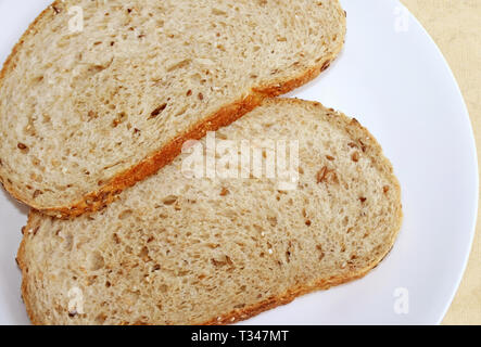Due fette di grano intero pane su una piastra bianca Foto Stock