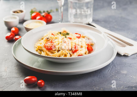 Deliziose le linguine con crema di salmone e pomodori. Spaghetti con erbe e salmone fresco Foto Stock