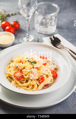 Deliziose le linguine con crema di salmone e pomodori. Spaghetti con erbe e salmone fresco Foto Stock