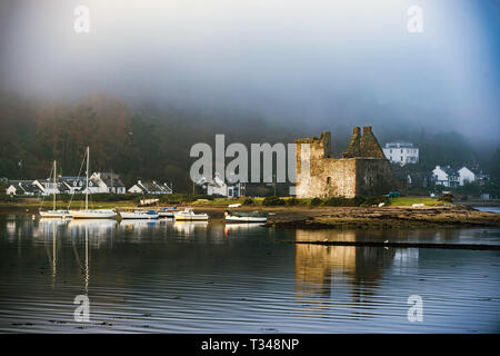 Lochranza Castle e bay, Isle of Arran, Scozia. Guardando attraverso un misty bay verso il castello con barche a vela sull'acqua. Foto Stock