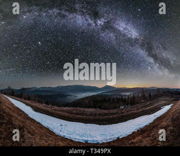 La molla notte stellata Carpazi plateau paesaggio con coperte di neve ridge cime nel lontano e la Via Lattea nel cielo, Ucraina. Foto Stock