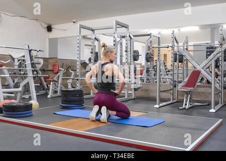 Adulto bella bionda femmina facendo stretching a praticare yoga in palestra. Foto Stock