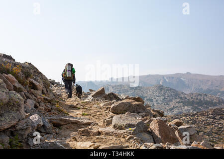 Escursionista e il suo cane a camminare su un sentiero di montagna, Stati Uniti Foto Stock