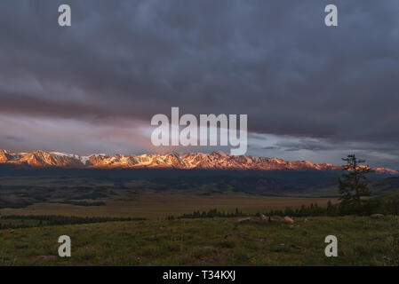 Incredibile sunrise con belle nuvole sul cielo sopra le montagne innevate, la valle e la foresta sulle pendici a nuvoloso meteo Foto Stock