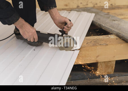 Operaio edile segatura di lamiera di acciaio con profilo trapezoidale Foto Stock