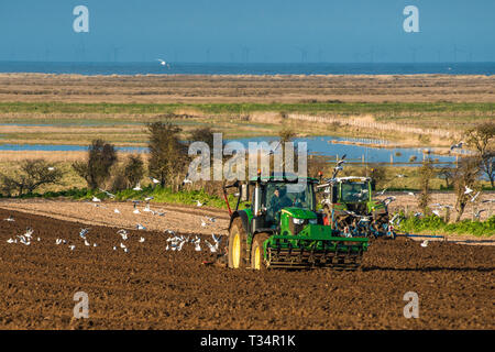 I trattori di effettuare profonde sagomatura letto seguita da semina i campi Inizio tempo di molle a Burnham Overy in North Norfolk, East Anglia, England, Regno Unito Foto Stock