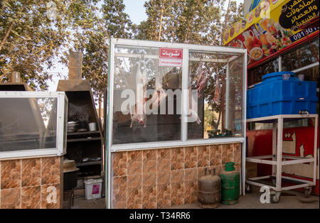 Karima, Sudan, Febbraio 8, 2019: dietro il vetro built-in stazione alla griglia in un ristorante di sudanesi con due chef agnello di elaborazione, carni di montone, di pecora e di capra Foto Stock