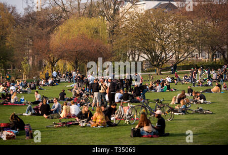 Amburgo, Germania. 06 apr, 2019. Numerose persone sedersi al sole su un prato sul Alster esterno. Credito: Daniel Bockwoldt/dpa/Alamy Live News Foto Stock