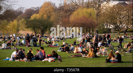 Amburgo, Germania. 06 apr, 2019. Numerose persone sedersi al sole su un prato sul Alster esterno. Credito: Daniel Bockwoldt/dpa/Alamy Live News Foto Stock