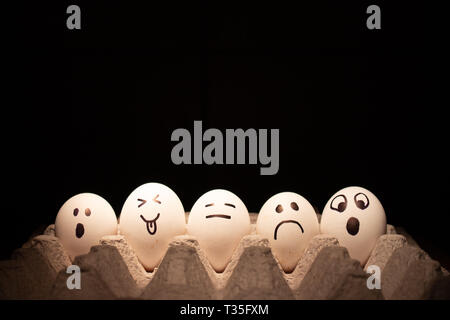 Di pollo o di uova di pasqua con facce buffe su sfondo nero. Foto Stock