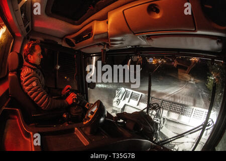 Una vista dalla cabina come un uomo aziona un gatto delle nevi la preparazione di piste da sci di notte francesi nella località alpina di Courchevel, Savoie. Gatto delle Nevi. Foto Stock