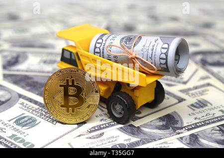 Bitcoin è sullo sfondo del dumper, che è caricato con un fascio di fatture del dollaro. Il concetto di prezzi elevati Bitcoin contro il dollaro USA Foto Stock