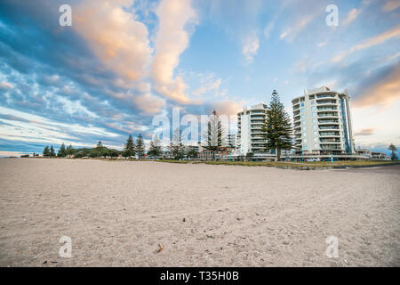 Mount Maunganui twin tower apartment edifici dalla spiaggia al crepuscolo sotto interessante formazione delle nuvole. Foto Stock