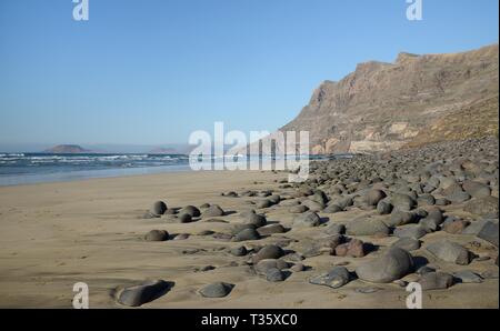 Spiaggia di Famara e scogliere con Graciosa isola sullo sfondo, Lanzarote, Isole Canarie, febbraio. Foto Stock