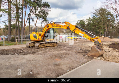 Giallo cingolati Caterpillar JCB JS130 LC impianto pesante escavatore escavatore cingolato con benna convogliatore ad RHS Gardens, Wisley, Surrey, Regno Unito Foto Stock