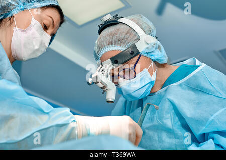 Il team di chirurghi fa un intervento invasivo. Ritratto di chirurghi di close-up. Lavorare con uno strumento di coagulazione, coagulazione vascolare. Foto Stock