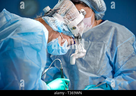Il team di chirurghi fa un intervento invasivo. Ritratto di chirurghi di close-up. Lavorare con uno strumento di coagulazione, coagulazione vascolare. Foto Stock