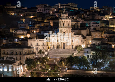 Palazzi illuminati in collina antica città di Modica Alta, famosa per la sua architettura barocca e Cattedrale di San Giorgio, Sicilia Foto Stock