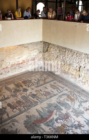 Vista turisti celebri mosaici e mosaici di arte di scene di caccia all'antica Villa Romana del Casale di Piazza Armerina, SICILIA, ITALIA Foto Stock