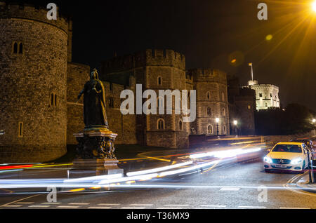 Una lunga esposizione shot della statua della regina Victoria al di fuori del Castello di Windsor di notte che conduce alla luce sentieri a sinistra passando le automobili. Foto Stock