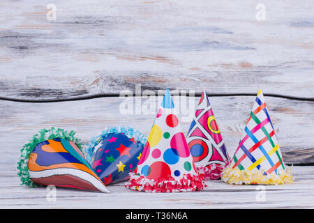 Colorate per i cappelli di carta per la festa di compleanno. Cono di festa tappi su sfondo di legno. Celebrazione di partito gli elementi. Foto Stock