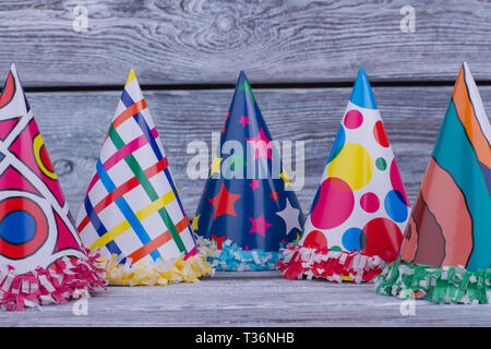 Raccolta di cappelli di compleanno su sfondo di legno. Set di cono in carta party tappi su tavole di legno. Materiali di consumo colorati per bambini partito. Foto Stock