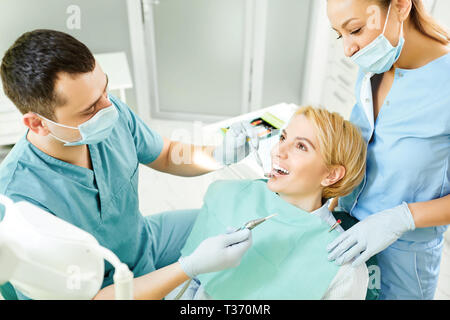 Dentista considera i denti del paziente ragazza Foto Stock