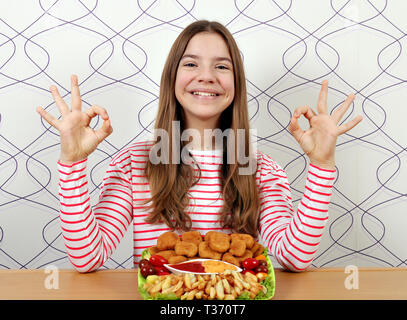 Felice ragazza adolescente con pepite di pollo e segno OK con la mano Foto Stock